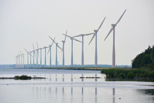 Een rij windturbines langs het water